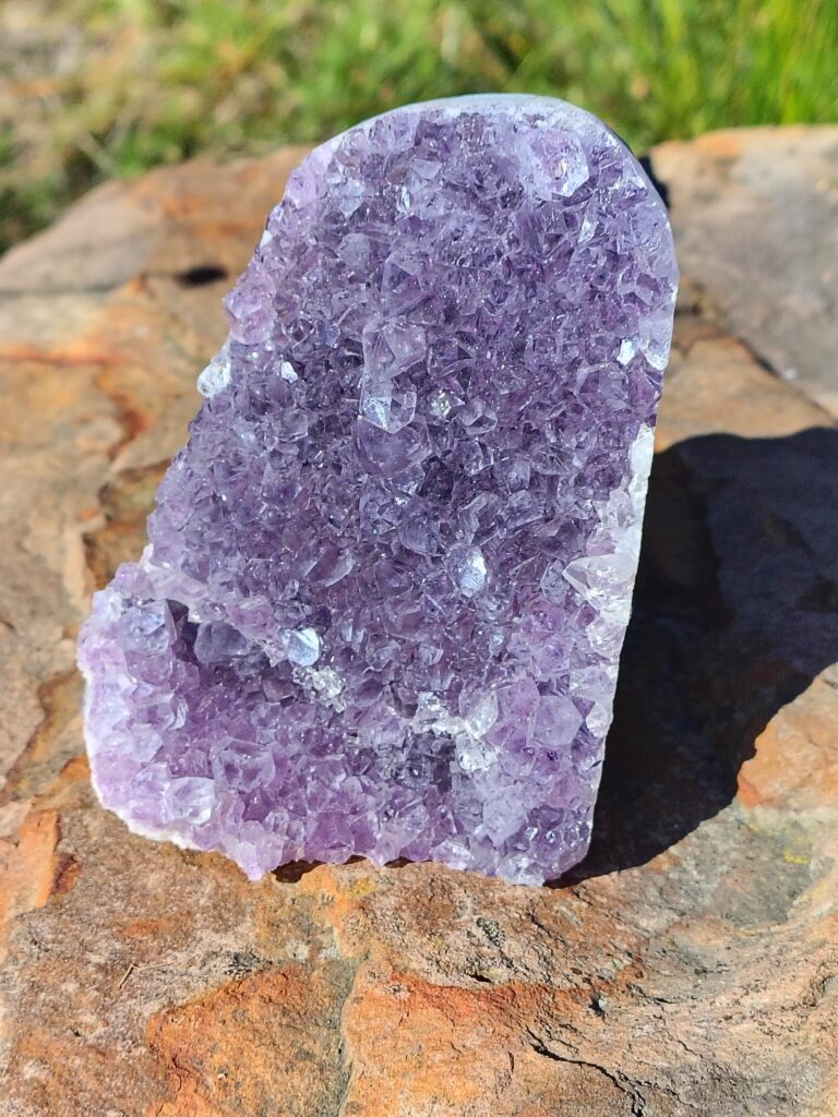 Amethyst statement piece with rich purple crystal formations and natural purple tones displayed on a rock.