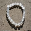 Clear Quartz stretch bracelet with transparent beads and natural inclusions resting on a rock outdoors.